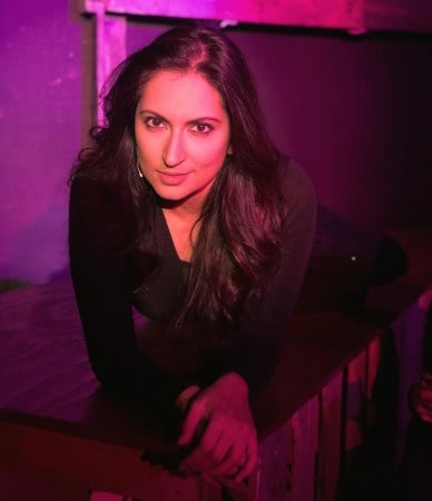 Zehra Fazel is wearing a black dress and posing for a photo.